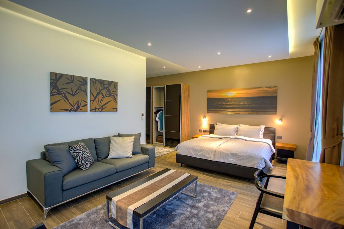 A modern bedroom with a bed, a sofa, a coffee table, and a painting on the wall.