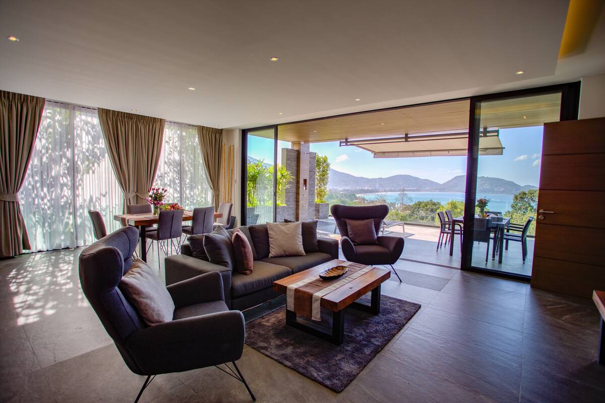 A modern living room with a sofa, armchairs, a coffee table, and a dining area.