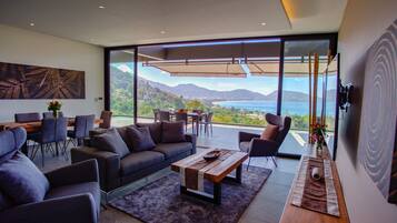 A modern living room with a large window offering a scenic view of mountains and a body of water.