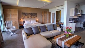 A modern hotel room with a large bed, a sofa, a dining table, and a kitchen area. - Ocean Rock Kalim (Patong)