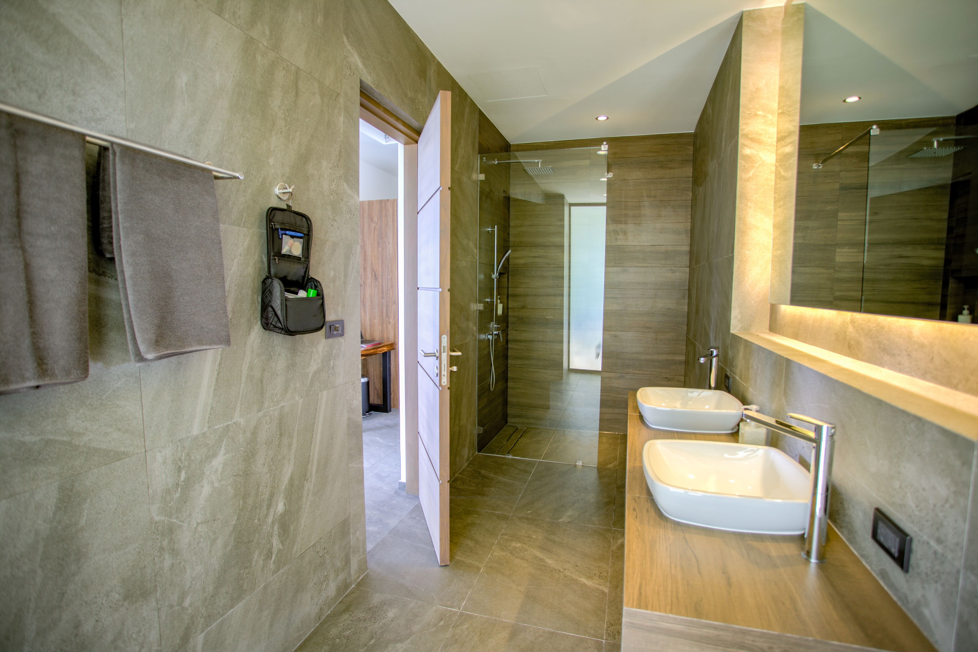 Ein modernes Badezimmer mit zwei Waschbecken, einer Dusche und einem Handtuchhalter.