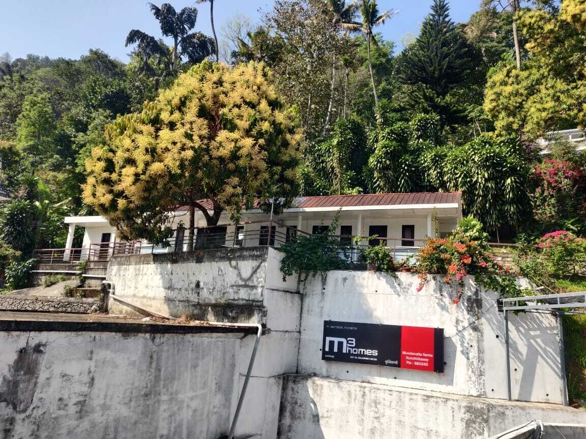 Eine Betonwand mit einem Schild für 'M3 Homes' und ein Gebäude mit rotem Dach im Hintergrund.