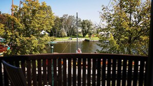 Una terraza con vistas a un lago, rodeada de árboles y un muelle con barcos.