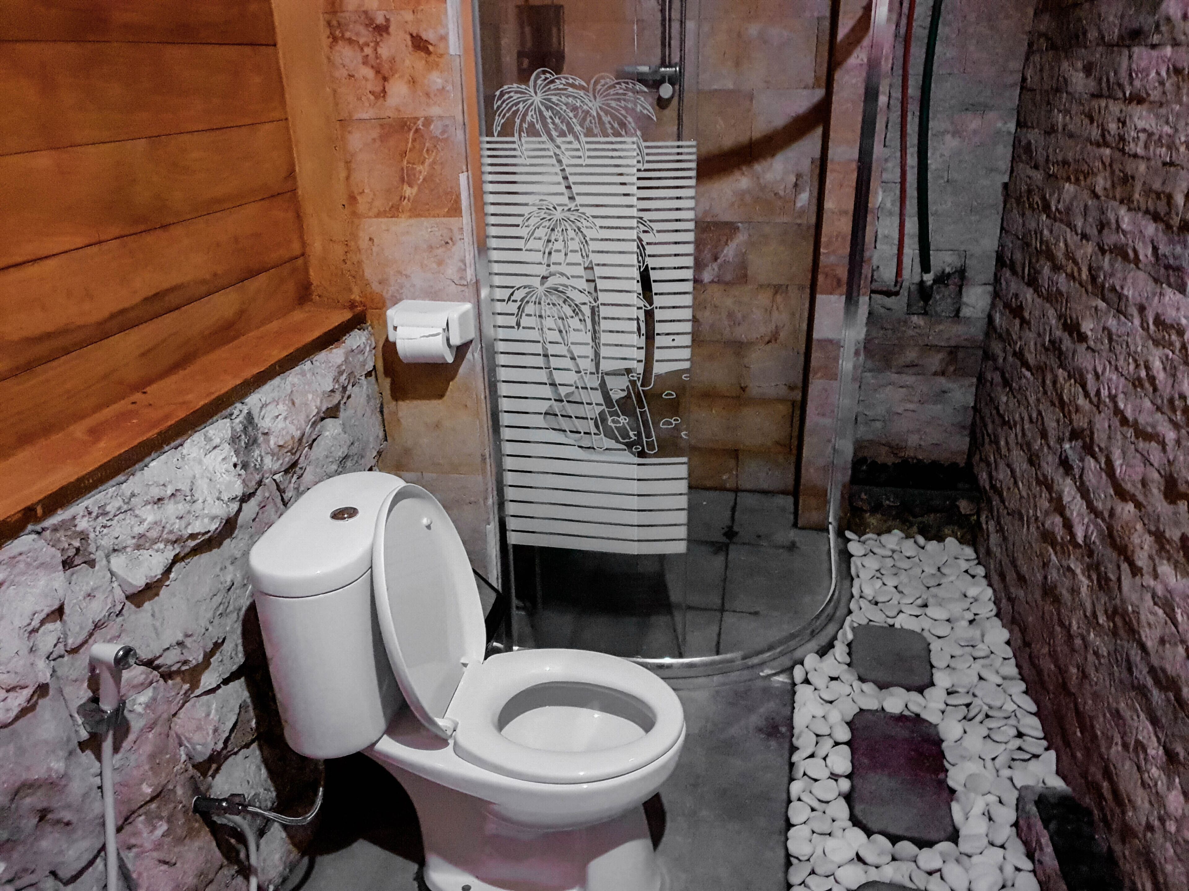 A bathroom with a white toilet, a shower area, and a towel rack with a striped towel.