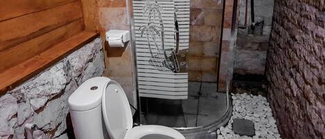 A bathroom with a white toilet, a shower area, and a towel rack with a striped towel.