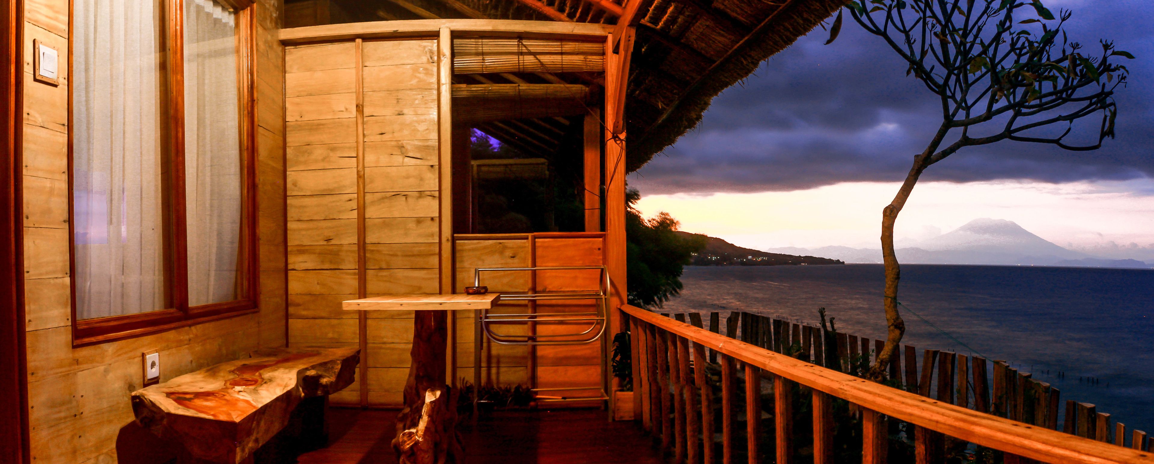 A wooden room with a view of the sea and a mountain.