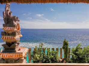 A coastal view with a stone structure and wooden fence. - Malibu Huts (Penida Island)