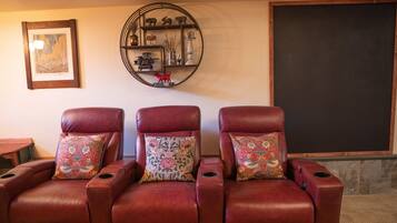 A room with three leather recliner chairs, each with a patterned cushion. A circular shelf with decorative items hangs on the wall above the chairs.