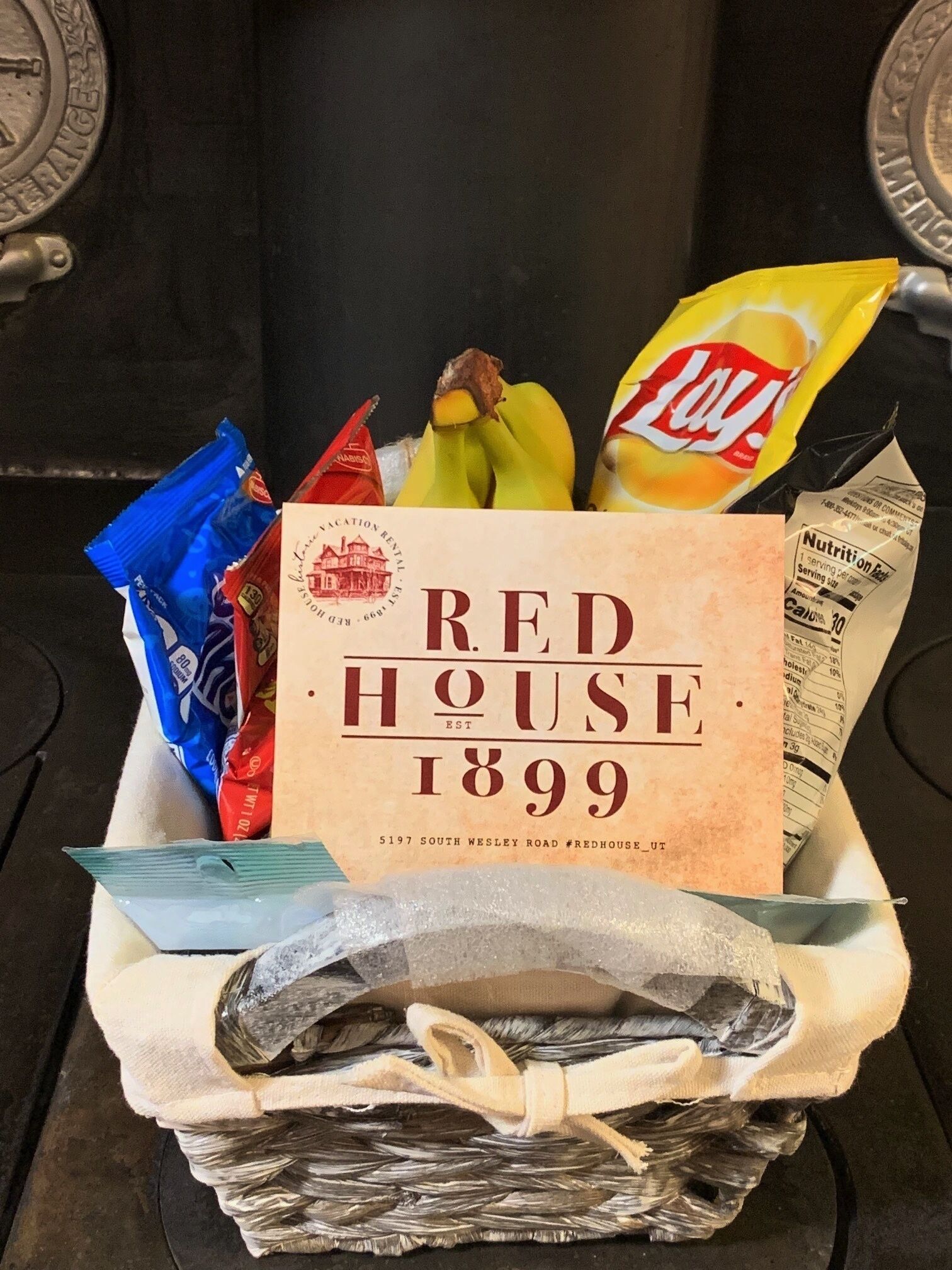 Un panier-cadeau portant l’étiquette « Red House 1899 », contenant des en-cas et une serviette.