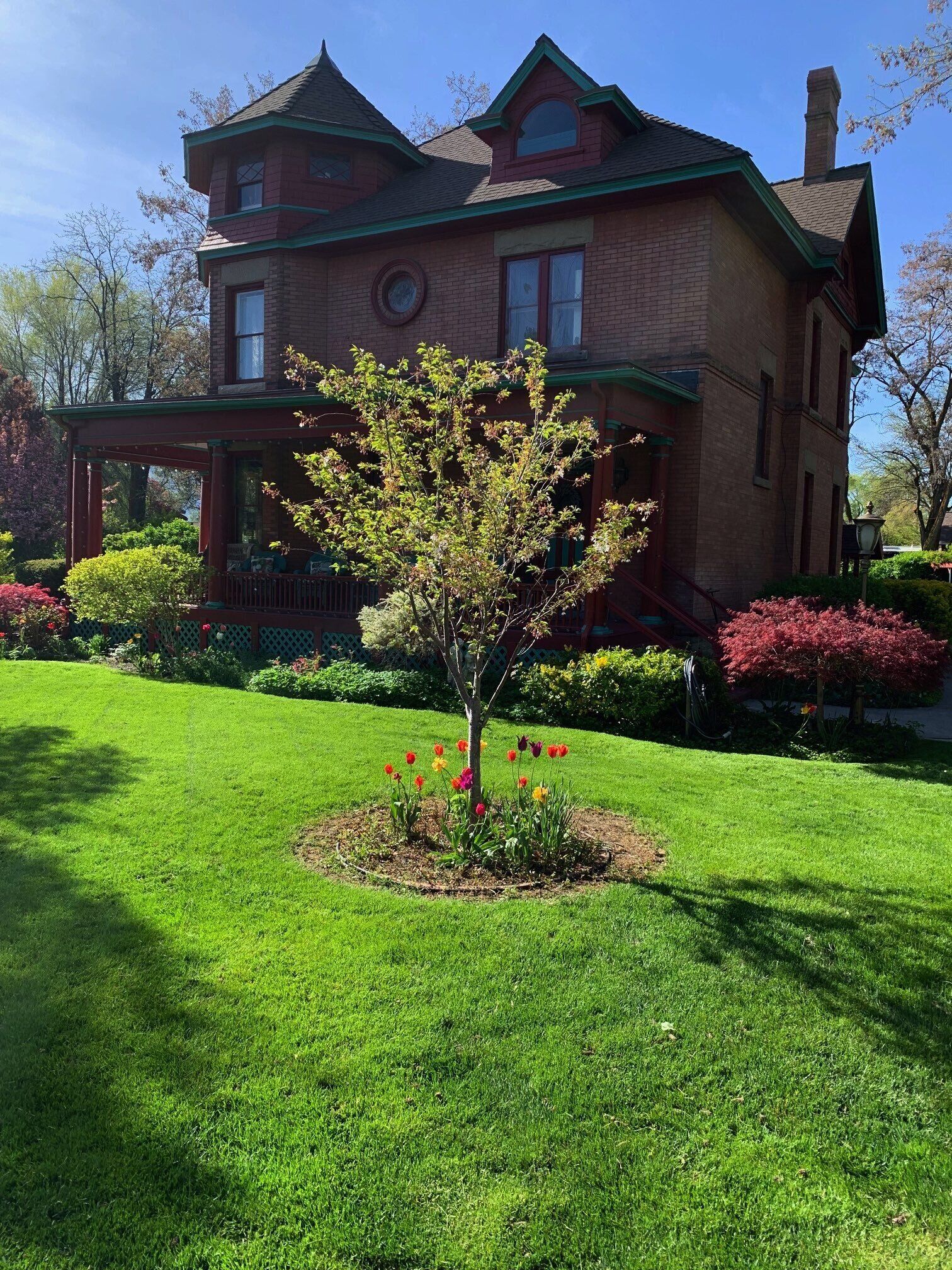 A two-story brick house with a green roof and a porch.