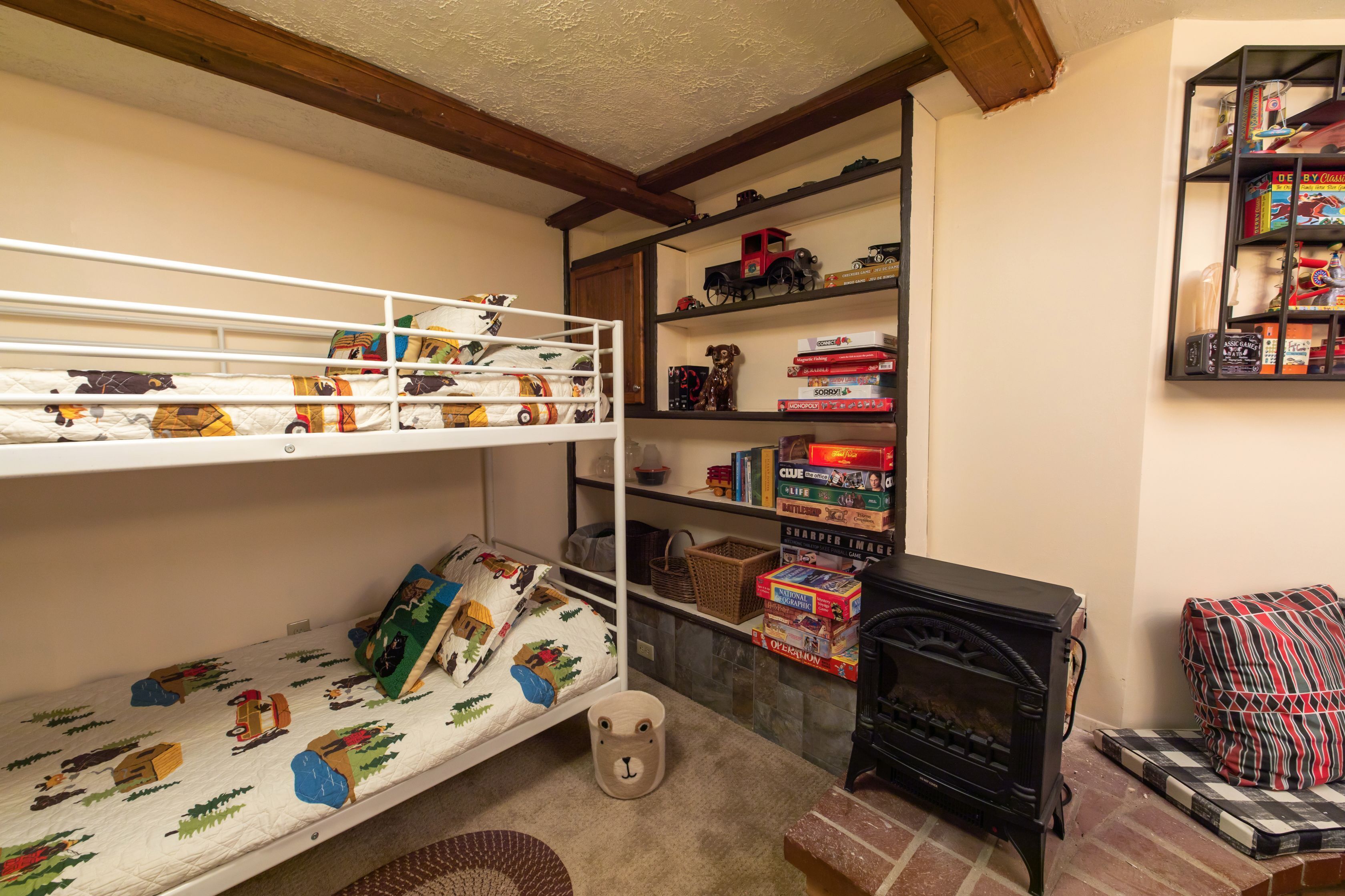 A bunk bed with a quilted mattress, a small wooden bear-shaped container, and a bookshelf with various items.