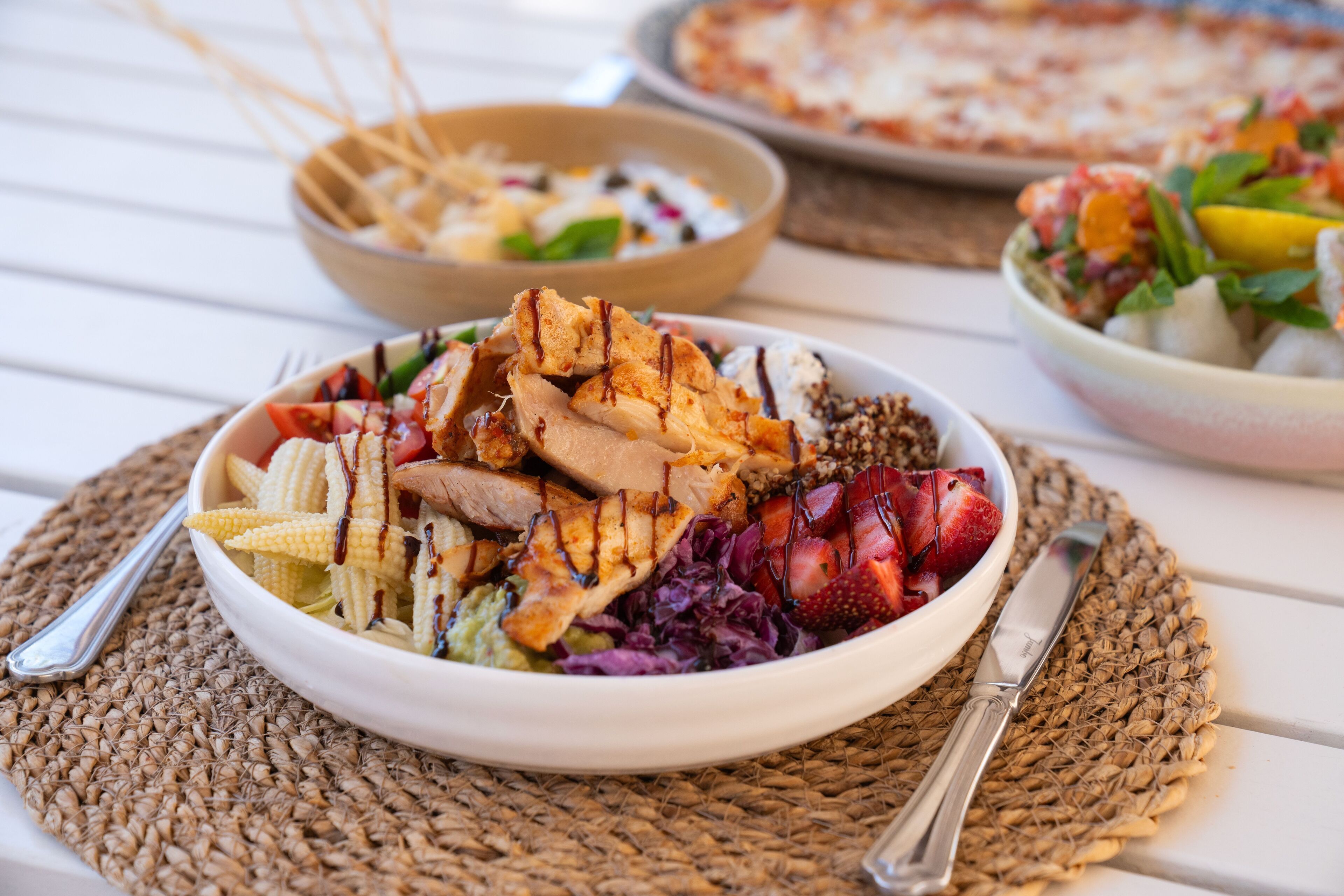 Ensalada con pollo a la parrilla, fresas y otras verduras sobre un posavasos tejido.