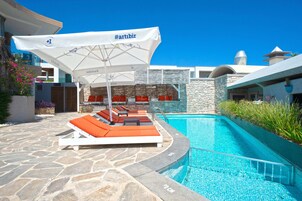 Una piscina al aire libre, sillones reclinables de piscina
