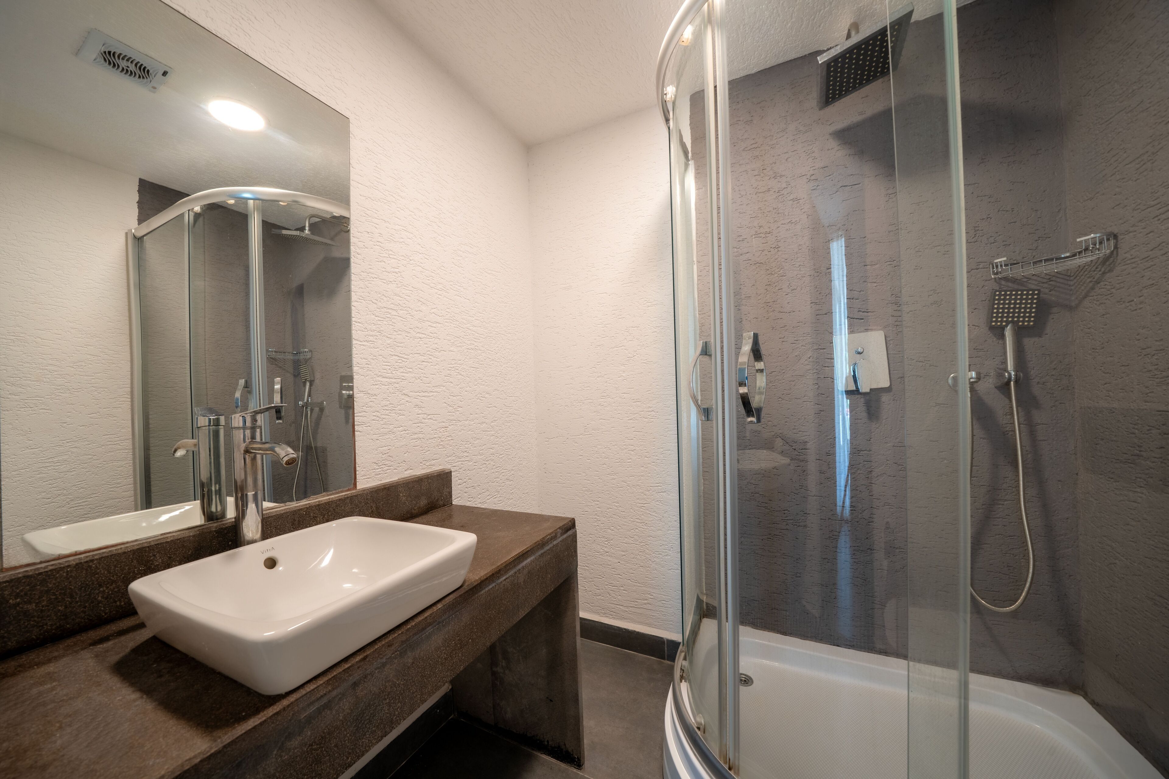 A modern bathroom with a white sink, a glass shower enclosure, and a bathtub.