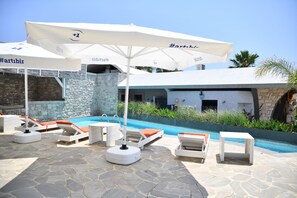 Una piscina al aire libre, sillones reclinables de piscina