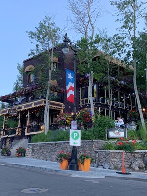 En restaurang med en Texas-flagga, uteservering och en stenmur med blomlådor.