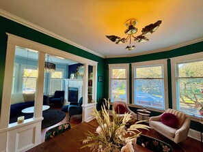 A cozy living room with a fireplace, comfortable seating, and large windows offering a view of the outdoors. - Boutique Chic Garden Retreat a Fremont Oasis w/ a BBQ, fire pit & outdoor dining (Seattle)