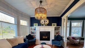 A living room with a fireplace, blue sofas, a round coffee table, and a chandelier.