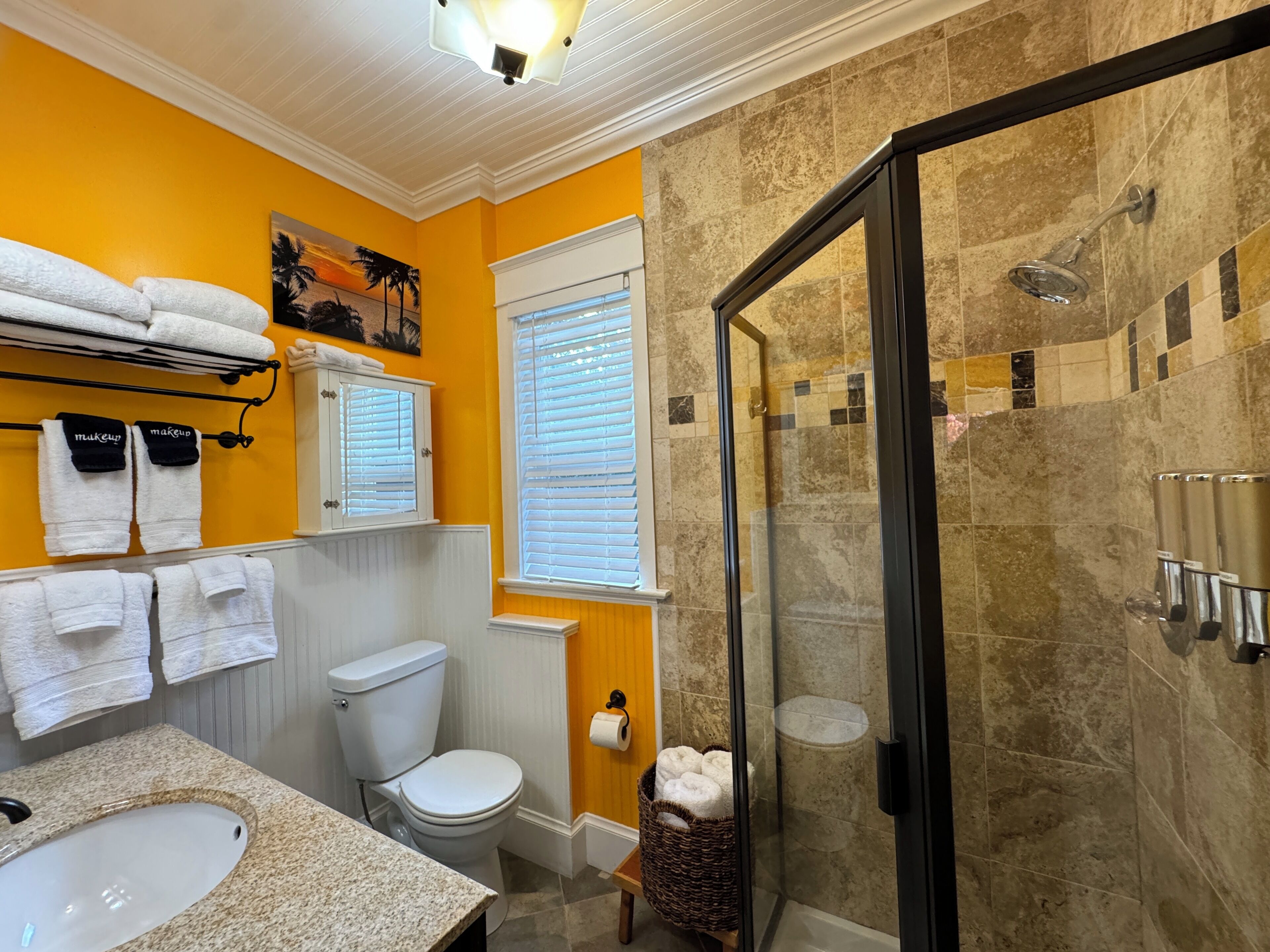Une salle de bain avec une douche à parois de verre, des toilettes, un lavabo et des serviettes rangées sur un porte-serviettes.