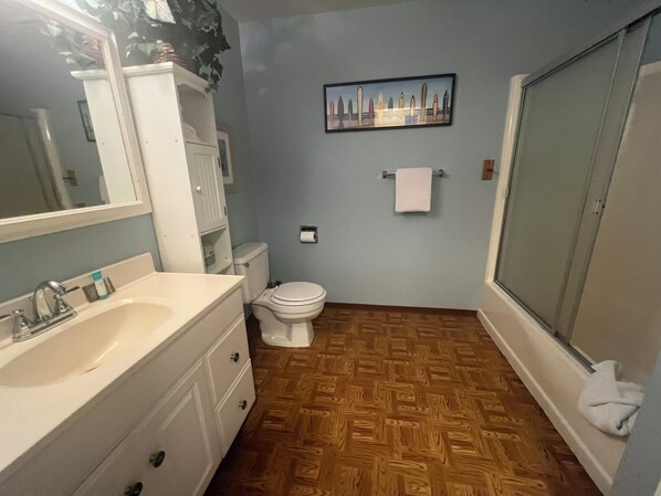 A bathroom with a white sink, toilet, and shower. There is a painting on the wall and a towel hanging on the shower door. - 4Bed/2Bath Pet Friendly, Fenced Back Yard, Steps to Beach Access (Seaside)