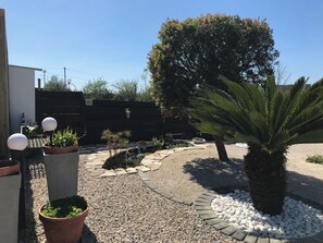 A garden with a palm tree, potted plants, a small pond, and a pathway. -  Cottage for 4 people - 39 m2 (Alcobaça, Leiria)