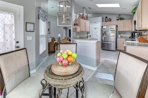 Una cocina moderna con una isla central, electrodomésticos de acero inoxidable y una zona de comedor con mesa y sillas.