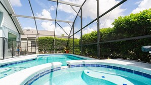 An indoor swimming pool with a clear view of the sky and surrounding greenery.