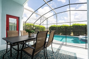 Un patio cubierto con piscina, sillas y una mesa.