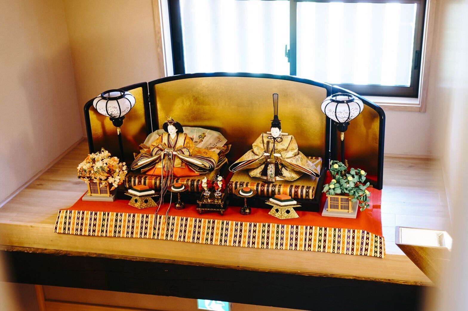 A traditional Japanese tea ceremony setup with a tatami mat, a tea table, a tea caddy, a tea bowl, a tea scoop, and a tea kettle.