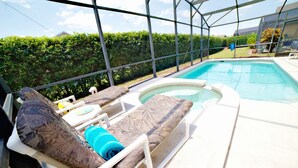A pool area with lounge chairs and a hot tub.