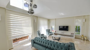 Un salón amplio con un sofá grande, un televisor y una mesa de centro.