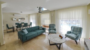 Amplia sala de estar con sofá, dos sillones, una mesa de centro y un comedor con sillas y una mesa.