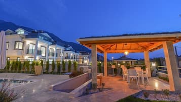 A modern outdoor patio area with a pergola, seating, and a pool.