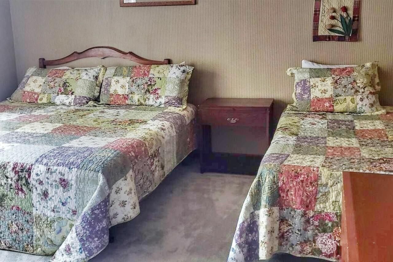 Una camera con due letti, ognuno con copriletto floreale, una testiera in legno e un comodino.
