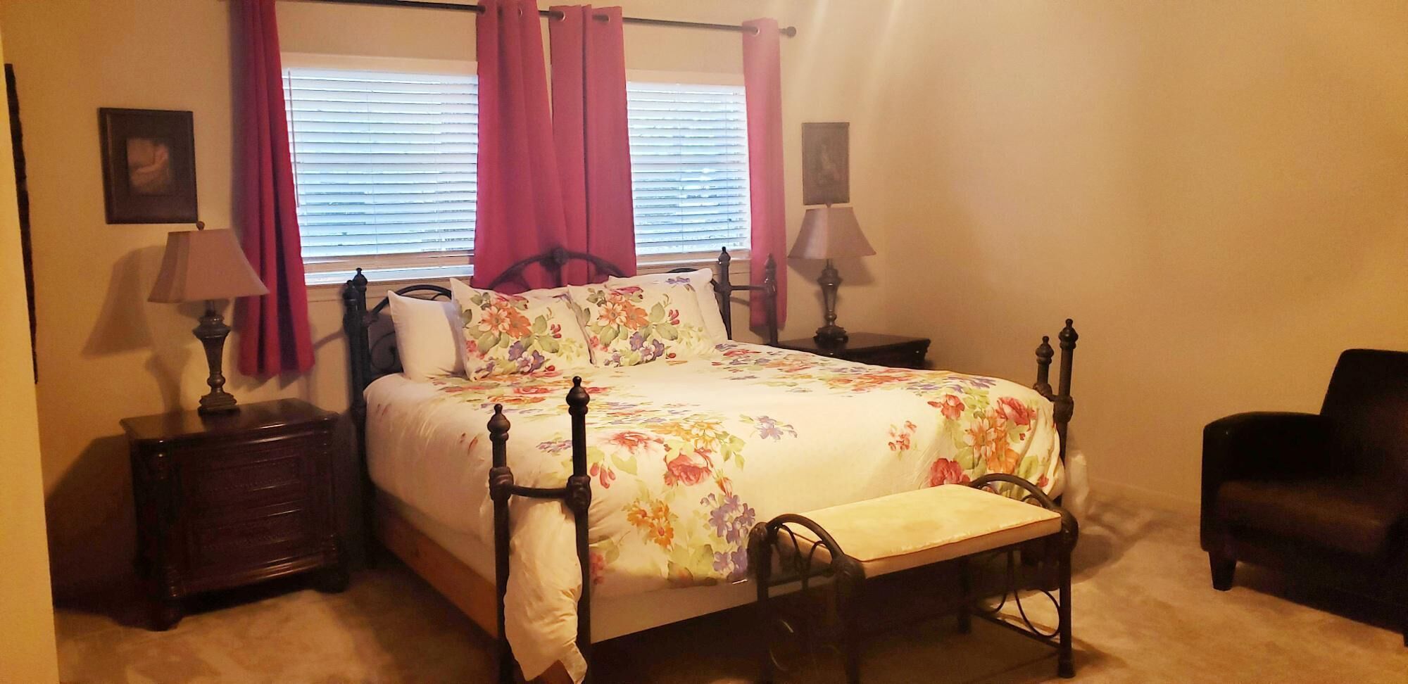 Une chambre à coucher avec un lit à baldaquin, une table de chevet, une chaise et une fenêtre avec des stores.