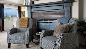 A living room with two houndstooth armchairs, a fireplace, and a view of the outdoors. - West Nine Stunning Views & Hot Tub (Port Angeles)