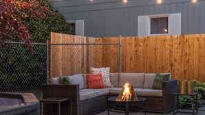 An outdoor seating area with a fire pit, wicker furniture, and a wooden fence. - West Nine Stunning Views & Hot Tub (Port Angeles)