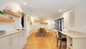 A modern kitchen with wooden shelves, a dining table, and chairs. - North Central Vacation Home (North Mackay)
