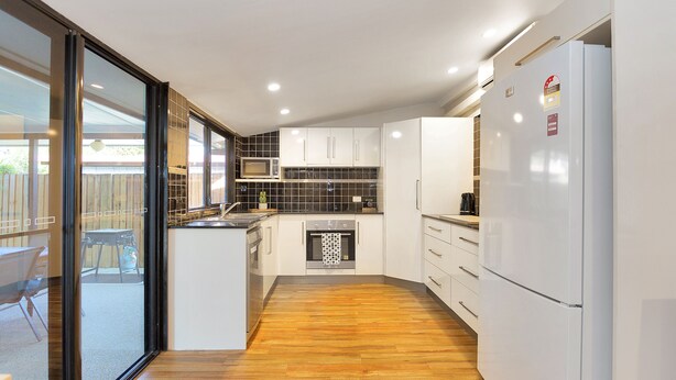 A modern kitchen with white cabinets, a built-in oven, and a refrigerator. - North Central Vacation Home (North Mackay)