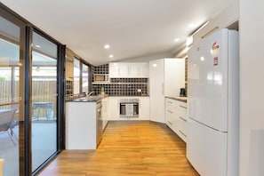 Une cuisine moderne avec des meubles blancs, un four encastré et un réfrigérateur.