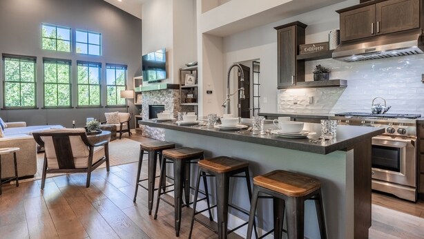 A spacious kitchen with a large island, bar stools, and a dining area with a sofa and chairs.
