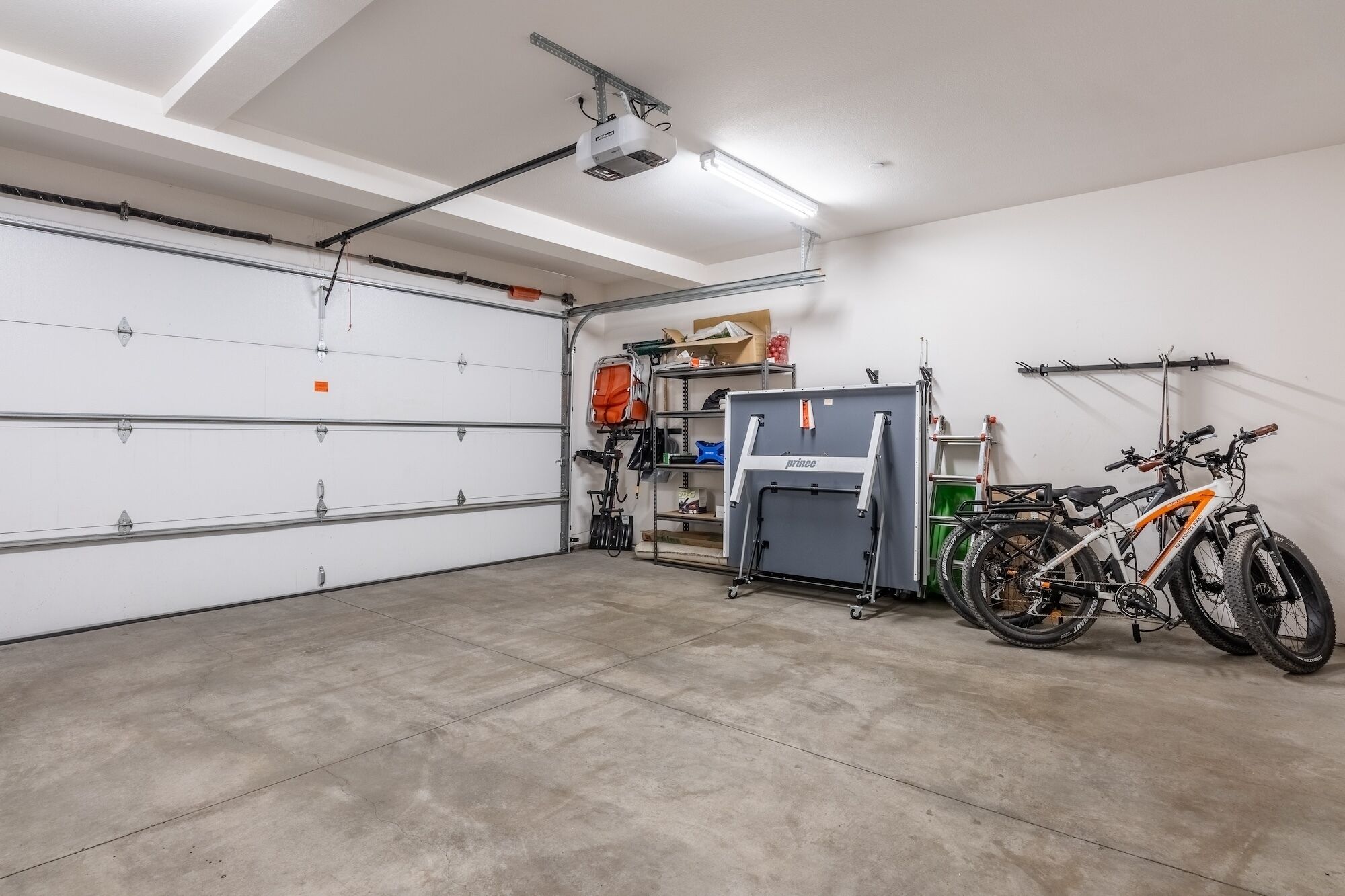 A garage with a white door, a projector, and two bicycles.