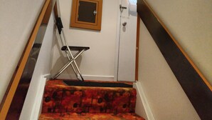 A staircase with a wooden handrail, a red carpeted step, a small folding chair, and a framed picture on the wall. - Toronto vacation home in North York with free parking (minimum 28 days stay)  (North York)
