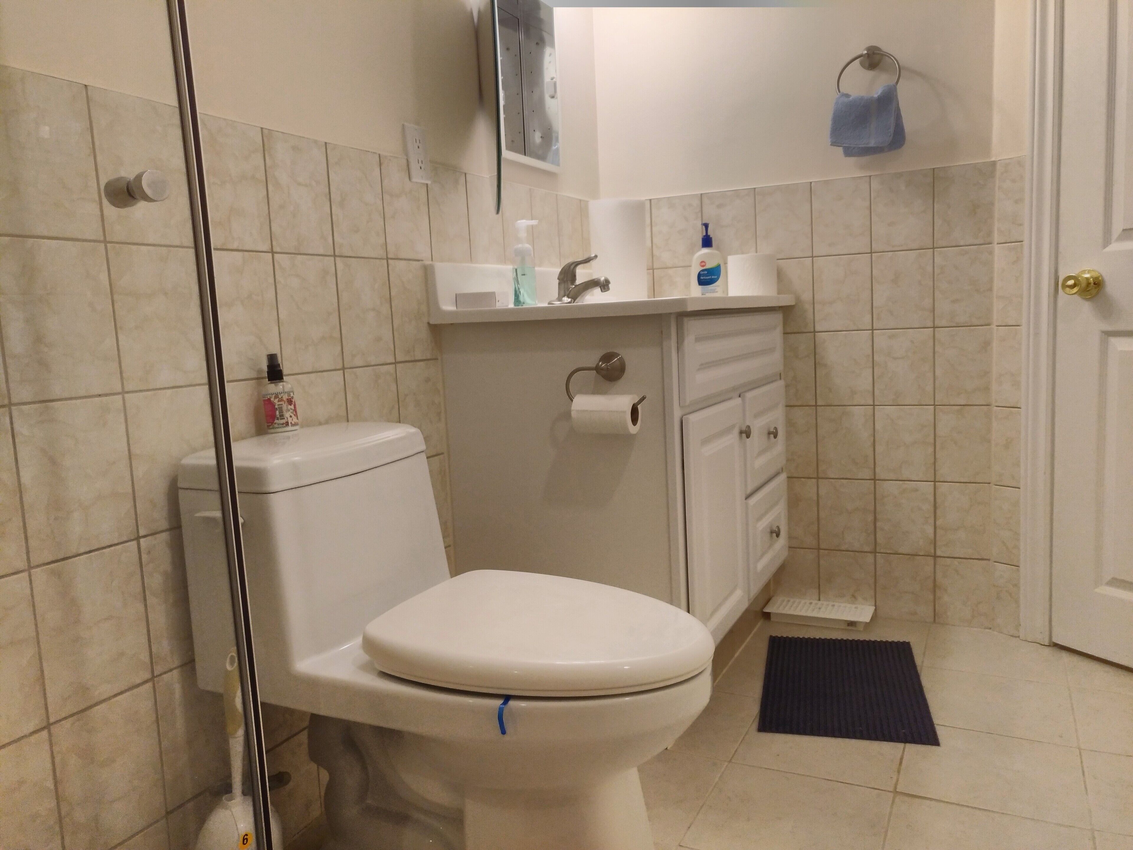 A bathroom with a toilet, a sink, a mirror, and a towel rack.