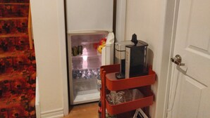 A compact kitchen with a white refrigerator, a coffee maker, and a red storage cart. - Toronto vacation home in North York with free parking (minimum 28 days stay)  (North York)