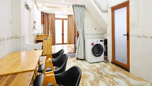 Une chambre d’hôtel compacte comprenant un coin repas, un lave-linge et une porte avec un cadre en bois.