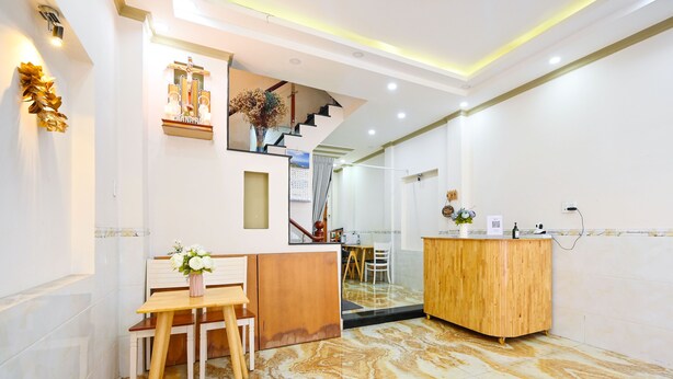 Un espace d’accueil comprenant un bureau en bois, un comptoir de réception, un escalier et un crucifix fixé au mur.