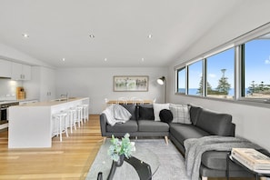 A modern living space with a kitchen, dining area, and seating area. - Surf Central (Lorne)