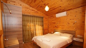 Ein schlicht eingerichtetes Schlafzimmer im Chalet-Stil mit einem Bett, einem Nachttisch, einer Klimaanlage und einem Vorhang.