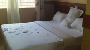 Een net opgemaakt bed met witte lakens en een dekenovertrek met bloemenprint.